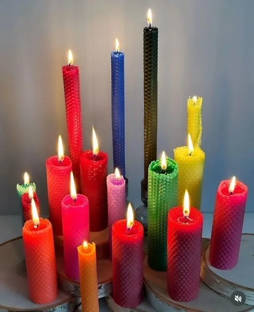 A cluster of red, green, yellow and blue candles of different heights, lit